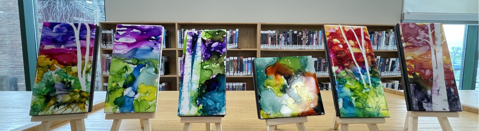 Glass tiles painted with ink and alcohol on display on mini easels